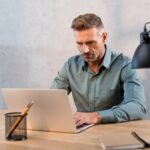 handsome-man-sitting-at-desk-and-using-laptop-in-o-2023-11-27-04-56-34-utc-1-1.jpg